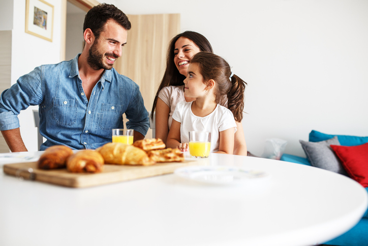 Husband and wife with they little daughter sitting at the kitchen table.Family portrait.